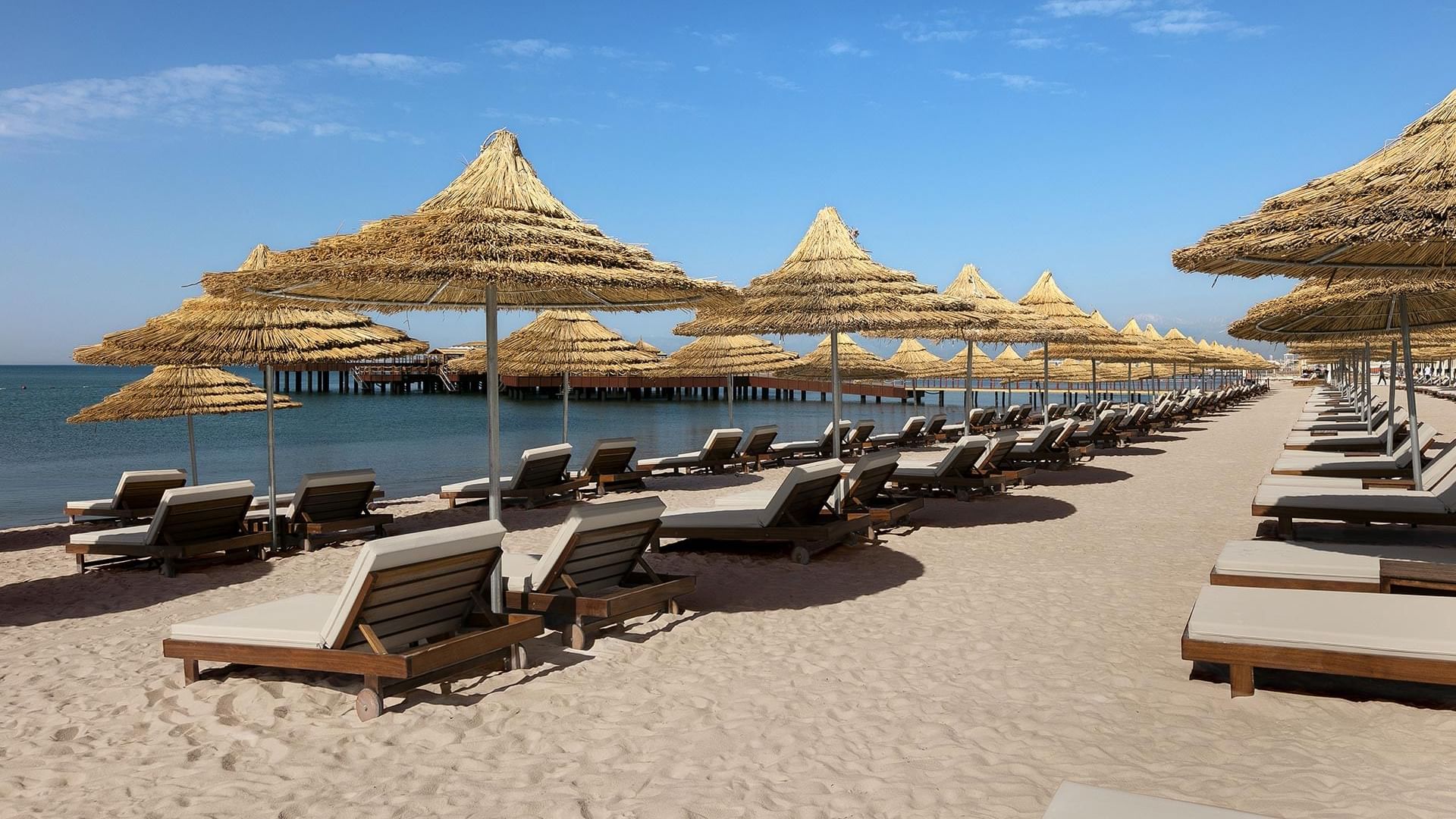 Sun loungers arranged by the sea on a sunny day in The Beach near Titanic Mardan Palace