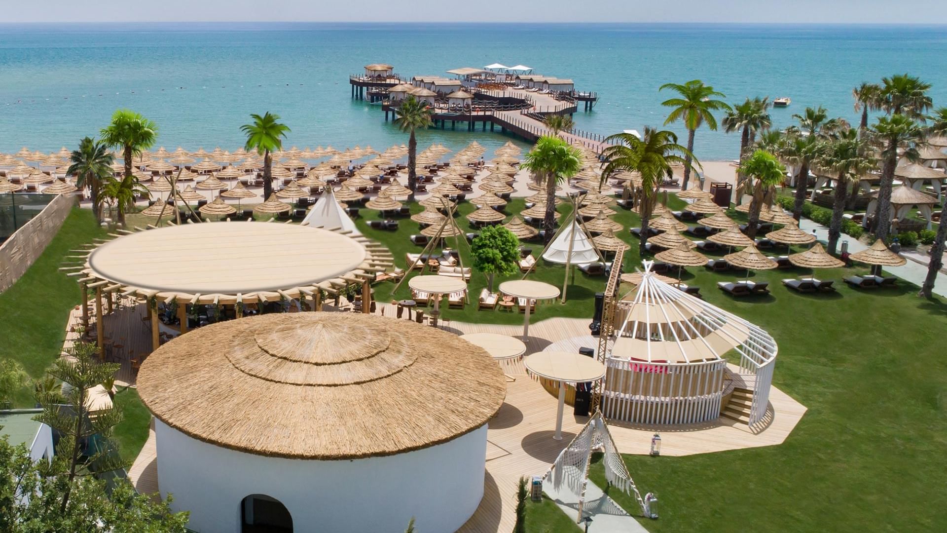 Aerial view of the sun loungers arranged by the sea and the wooden bridge deck near Titanic Mardan Palace