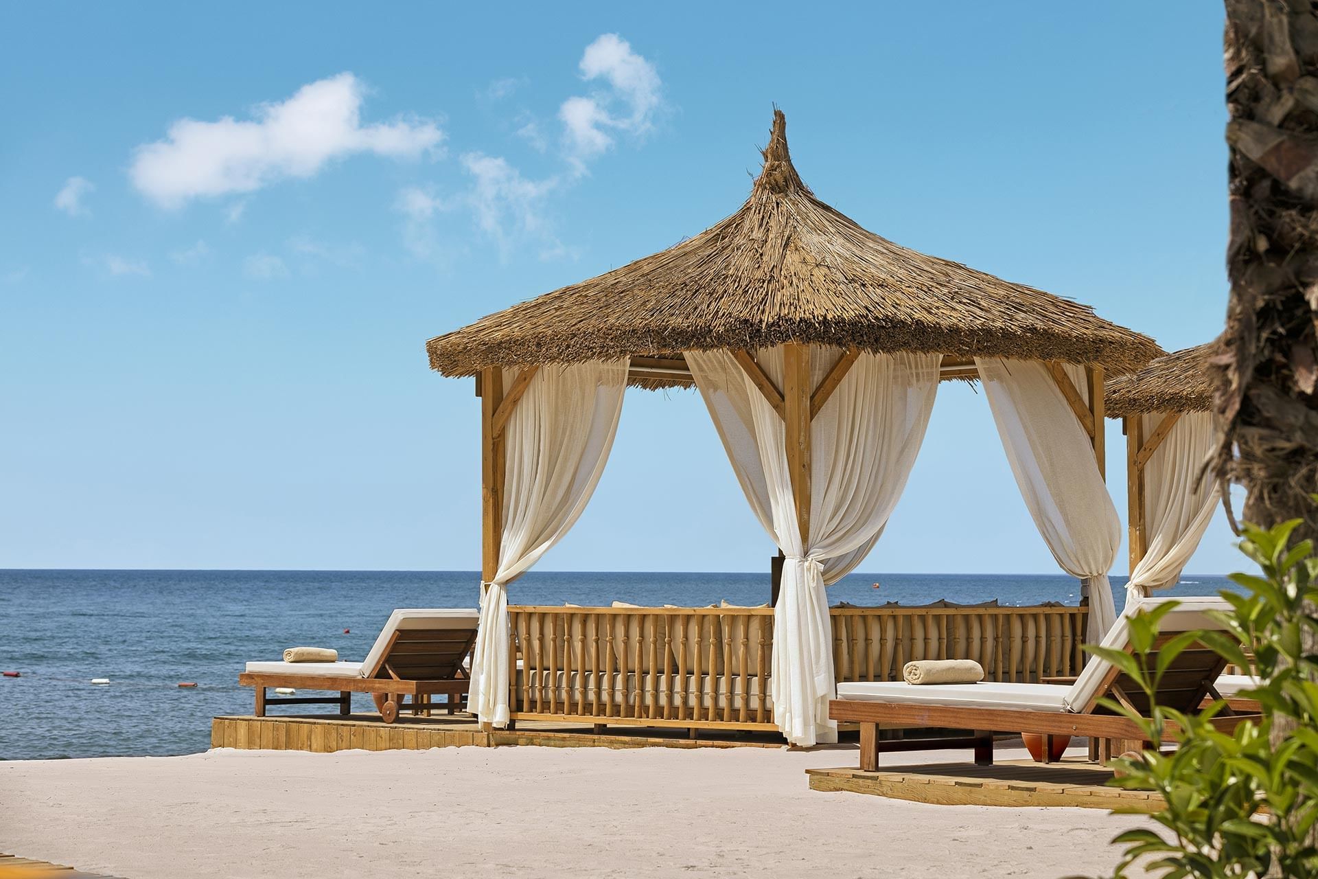 Beach side Cabana with white curtains and sun loungers at  Titanic Mardan Palace 