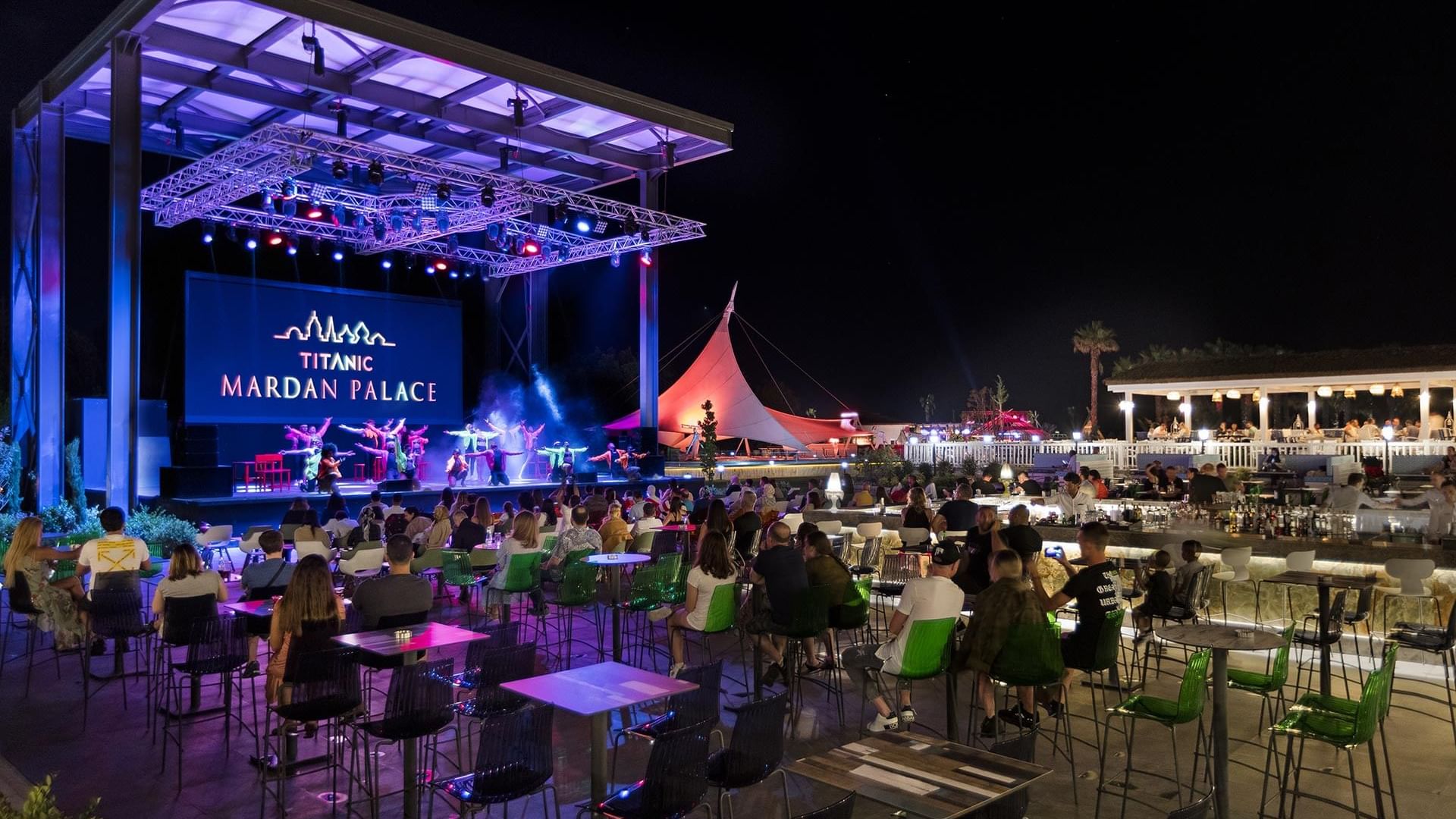 People dining outdoors at night in Nevizade Square Bar at Titanic Mardan Palace