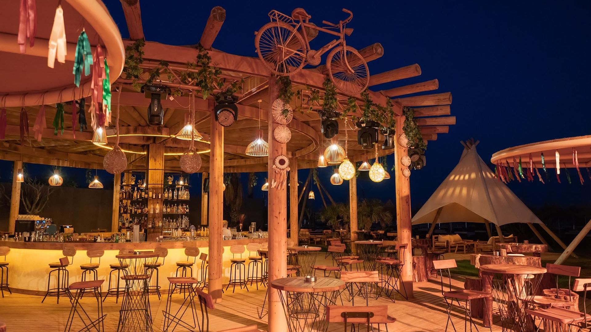 An outdoor dining area with tables and chairs in Mykonos Beach Club at Titanic Mardan Palace