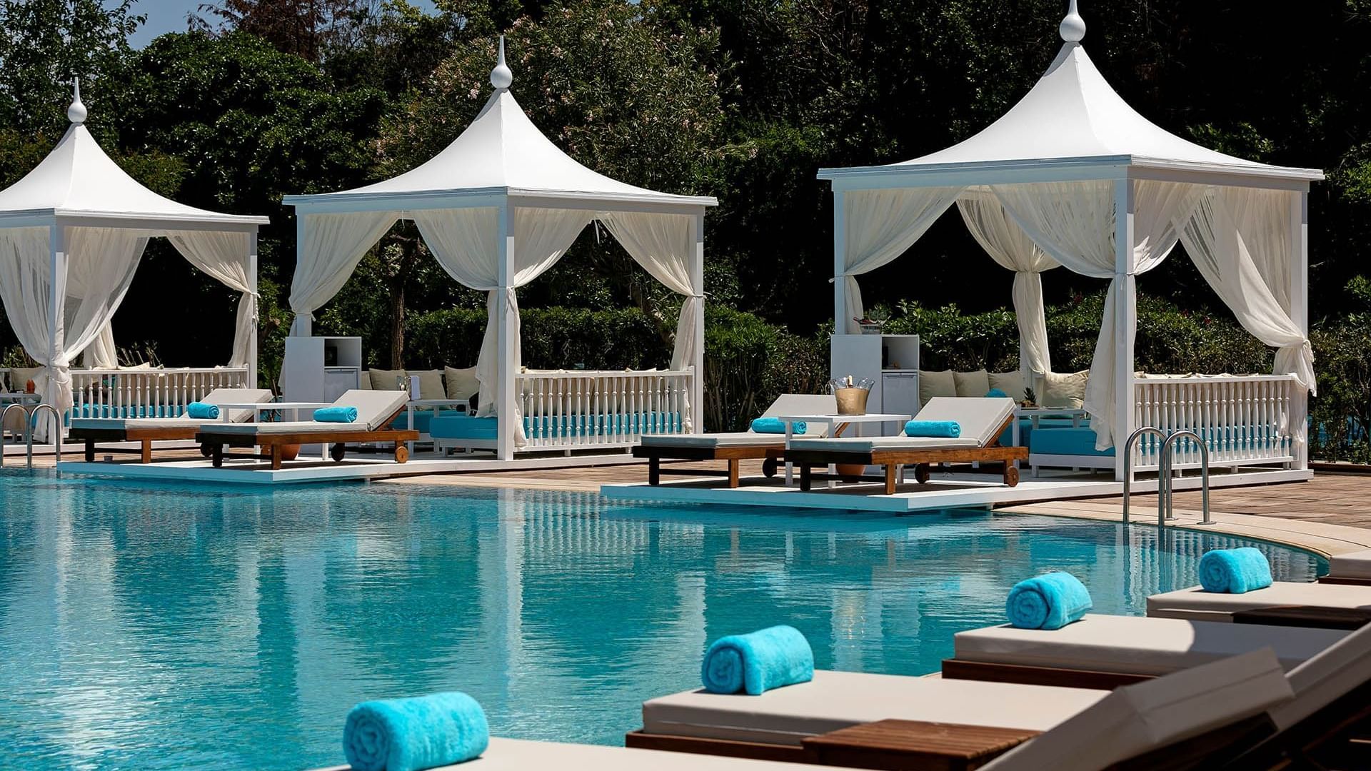 Sun loungers arranged by the pool outdoors on a sunny day at Titanic Mardan Palace