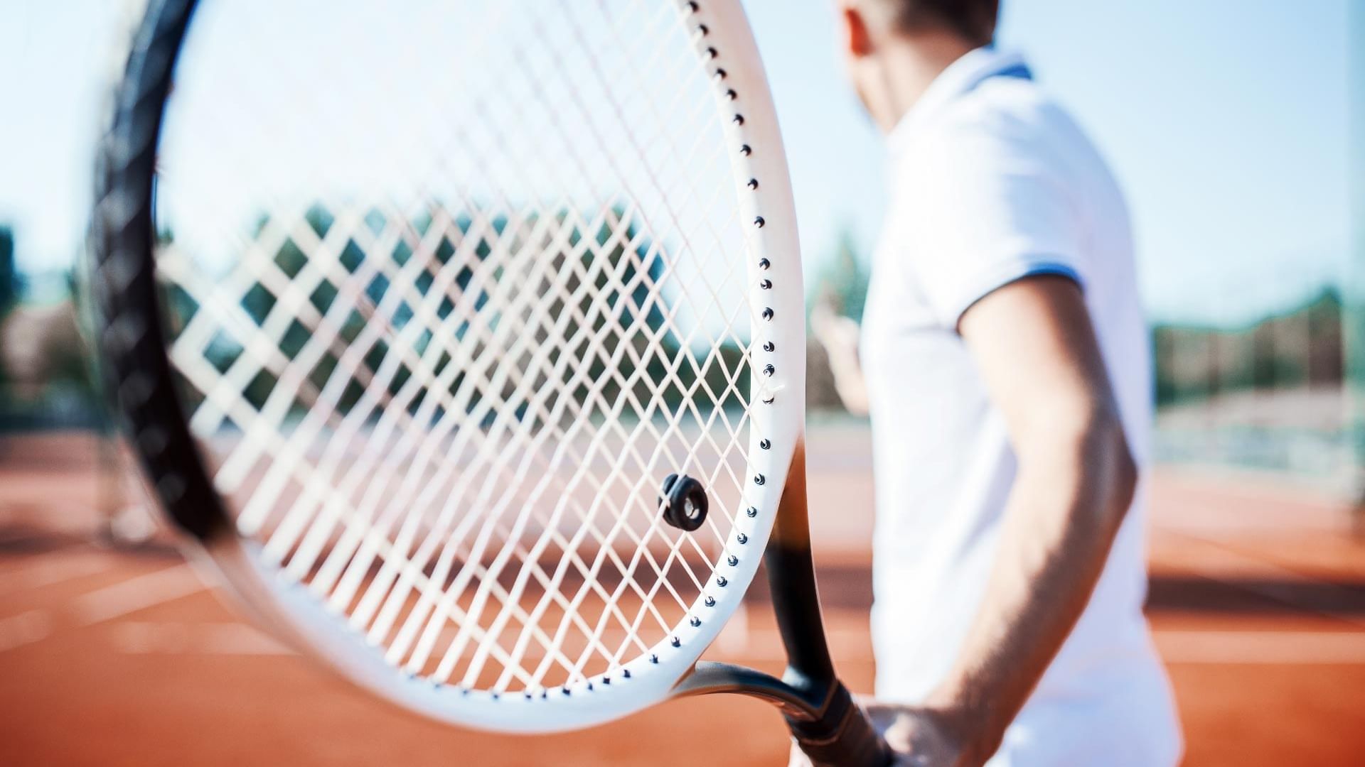 A man with a tennis racket and ready to take a shot in a tennis pit at Titanic Mardan Palace