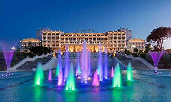 Titanic Mardan Palace facade at twilight with colorful illuminated fountains