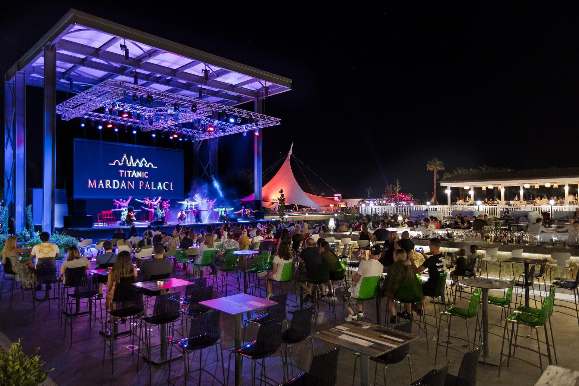 People dining outdoors at night in Nevizade Square Bar at Titanic Mardan Palace